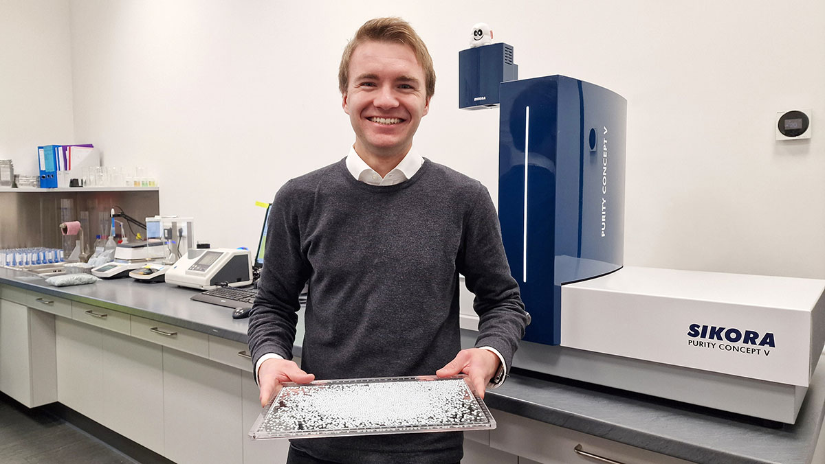 Cedric Steeg, Employee in Quality Assurance, holds material sample in front of the PURITY CONCEPT V.